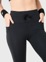 Calza deportiva de tiro alto con ajuste de cordón en la cintura y bolsillos laterales. Diseño ajustado al cuerpo con costuras reforzadas.