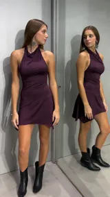 Vestido corto bordó con cuello halter y diseño sin mangas, de corte ajustado en el torso y falda con caída asimétrica.
