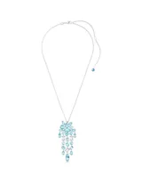 Colgante con cadena plateada y dije con forma de cascada de cristales facetados en tonos azules y blancos. El engaste está bañado en rodio.