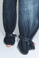 Jeans de tiro medio con diseño tipo balloon, cinco bolsillos y bajo ajustable con trabilla y botones. Cierre frontal con cremallera y botón metálico.