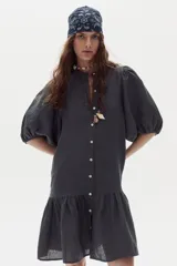 Vestido corto de lino color gris oscuro, con mangas abullonadas, cierre frontal con botones y volado en el ruedo.