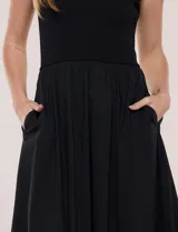 Vestido midi sin mangas de color verde militar, confeccionado con la parte superior en tejido de punto acanalado con cuello alto y falda acampanada de gran vuelo.