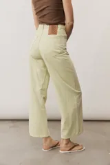 Pantalón de jean verde lima, de corte recto y tiro alto, con bolsillos traseros y etiqueta de cuero con logo en la parte posterior.