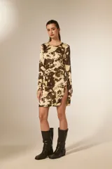 Vestido corto de manga larga con cuello redondo, confeccionado en tela satinada con estampado animal print tipo vaca. Presenta un diseño al cuerpo con pinzas y una abertura lateral en la falda.