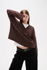 Sweater de punto a rayas horizontales color marrón y blanco, con cuello en V, capucha con cordones y cierre frontal parcial con botones. Presenta un diseño de manga larga con caída de hombros.