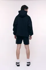 Canguro oversize confeccionado en denim negro 100% algodón, con capucha, cuello alto con cierre metálico frontal, bolsillo frontal tipo canguro y puños con elástico.