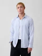 Camisa de lino de manga larga con diseño de rayas verticales en tonos celestes y blancos, cuello camisero clásico y cierre frontal de botones.