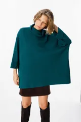 Sweater de tejido de punto suave en color beige, con silueta holgada, cuello alto y mangas tres cuartos con puños definidos.