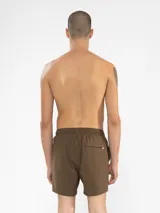 Short de baño azul marino con bordado de enredadera en la pierna izquierda. Tiene cintura elástica con cordón regulable, bolsillos laterales y trasero con cierre, y suspensor de malla fina hipoalergénico.