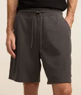Bermuda masculina de corte slim, confeccionada en tejido de algodón con felpa. Presenta cintura elástica con cordón ajustable, bolsillos laterales y una pequeña etiqueta aplicada en el ruedo.