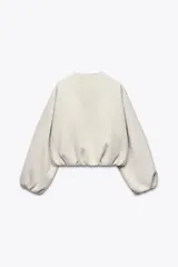 Chaqueta bomber de cuello redondo y manga larga con diseño holgado. Presenta cierre frontal con cremallera, bolsillos delanteros de vivo y acabados elásticos en los puños y el ruedo.