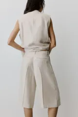 Bermuda de tiro alto en mezcla de lyocell, color beige, con piernas amplias, pinzas, raya planchada al frente y atrás, bolsillos al bies y bolsillos traseros insertados.