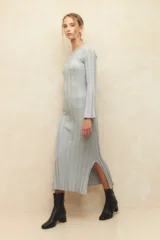 Vestido midi de punto acanalado en color gris, con mangas largas acampanadas y aberturas laterales en el ruedo. Presenta un diseño ajustado al cuerpo.