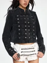 Chaqueta de denim estilo militar con cuello mao, cierre frontal con botones metálicos y detalles de trabillas horizontales. Presenta hombreras decorativas y diseño estructurado.