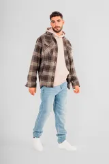 Sobrecamisa de hombre con cuello camisero, botones frontales y bolsillos de parche en el pecho. Presenta un estampado a cuadros en tonos marrones, negros y beige.