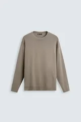 Jersey relaxed fit color beige, tejido en hilatura con viscosa de tacto suave. Presenta cuello redondo y manga larga, con acabados en rib.