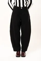 Pantalón de tiro medio con silueta curvada, más ancha en la zona de los muslos y rodillas, con cierre frontal de cremallera y botón.