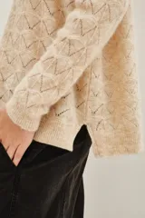 Sweater de punto con diseño calado geométrico, cuello redondo y mangas largas. Confeccionado en una mezcla de lana y alpaca, presenta una textura suave y ligera.
