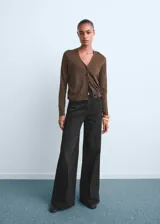 Pantalón de jean tiro alto con diseño wide leg, confeccionado en tejido de algodón con elasticidad. Cuenta con cierre frontal de cremallera y botón, trabillas para cinturón y cinco bolsillos.