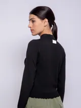 Polera negra de tejido de punto, manga larga y cuello alto.