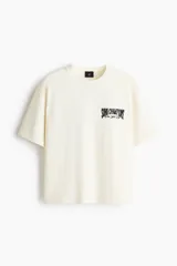 Remera de algodón en color blanco, de corte holgado, con cuello redondo acanalado, mangas cortas y hombros caídos. Presenta un pequeño estampado en el pecho con la inscripción "SOHO CHAMPIONS New York City".