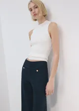 Pantalón azul marino de tiro medio y corte flare, con bolsillos frontales decorados con botones dorados.