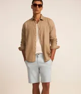 Bermuda masculina slim confeccionada en sarga de algodón con elastano, con bolsillos laterales, bolsillos traseros con botón, trabillas en la cintura y cierre frontal de botón y cremallera.