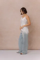 Musculosa de satén color crema con breteles finos regulables, escote en V y detalles de encaje en el escote, en diagonal sobre el delantero y en el ruedo.