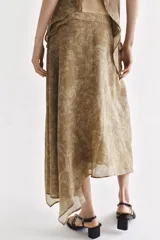 Falda midi de tiro alto y diseño asimétrico con cierre frontal cruzado y botón decorativo. Presenta una textura rústica con estampado sutil y forro interior marrón.