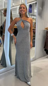 Vestido largo plateado de fiesta con acabado brillante, escote halter cruzado con abertura tipo lágrima y diseño al cuerpo con caída fluida.