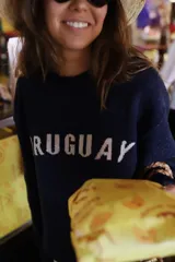 Sweater de punto color azul marino con cuello redondo y mangas largas. Presenta la palabra 'URUGUAY' tejida en color blanco en el frente.