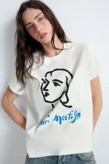 Remera de algodón de corte regular con cuello redondo y manga corta. Presenta un estampado frontal con un dibujo lineal de un rostro y la firma de Henri Matisse en color azul.