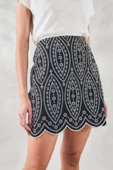 Minifalda negra con bordado blanco de motivos geométricos y terminación festoneada.