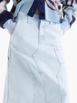 Pollera midi de denim en color azul claro con efecto lavado. Presenta un diseño de corte recto con costuras decorativas visibles, bolsillos frontales tipo cargo y una abertura central en el ruedo.