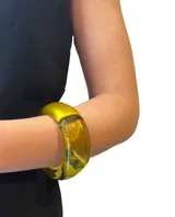 Pulsera rígida de resina color amarillo traslúcido, con forma redondeada y diseño moderno.