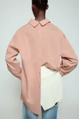 Camisa de cuello solapa y manga larga con estampado de rayas verticales. Presenta un bolsillo de plastrón en el delantero, cierre frontal con botones y detalle de botones en la espalda. Su diseño cuenta con un bajo asimétrico y aberturas laterales.