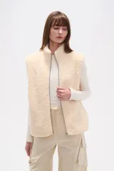 Chaleco sin mangas de textura peluche (teddy) color crema, con cuello alto y cierre frontal de cremallera.