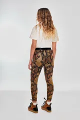 Pantalón tipo babucha con estampado de piel de serpiente en tonos marrones y naranjas, con cintura elástica negra.