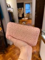 Clutch rectangular color rosa con bordado floral de encaje y cierre metálico dorado.