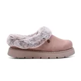 Zueco tipo pantufla de diseño casual, confeccionado con parte superior textil de aspecto gamuzado en color rosado. Presenta un interior y ribete de piel sintética, suela de plataforma plana con absorción de impactos y un pequeño aplique metálico en forma de corazón en el lateral.