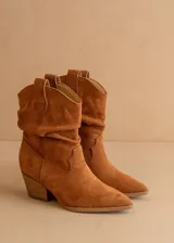 Bota texana de caña media confeccionada en gamuza color suela, con diseño arrugado en el empeine, puntera fina y taco cuadrado de altura media.