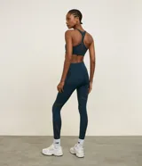 Legging deportiva de tiro alto en color azul oscuro, confeccionada en microfibra de poliamida y elastano. Presenta recortes laterales en tela de malla para mayor transpirabilidad y un ajuste ceñido al cuerpo, ideal para actividades de alta intensidad.