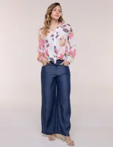 Camisa de gasa blanca con estampado floral multicolor, cuello con solapa, mangas largas y cierre frontal con botones. Cuenta con terminación delantera anudada y espalda más larga.