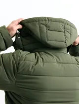 Campera acolchada de color gris, con capucha desmontable, cierre frontal y bolsillos laterales con cremallera. Presenta un diseño de costuras horizontales y detalles en color naranja en los tiradores de los cierres.