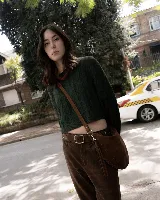 Bolso tipo hobo de gamuza color marrón, con diseño de costuras trenzadas en los bordes y tiradores de cuero anudados. Cuenta con una correa larga ajustable y desmontable, permitiendo su uso al hombro o cruzado.