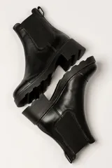 Bota tipo Chelsea de cuero color verde oliva, con paneles laterales elásticos negros y suela track de goma negra con taco cuadrado.
