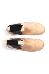 Bota estilo botineta deportiva color beige, con elásticos laterales negros, suela blanca y tiradores en la parte trasera y delantera.