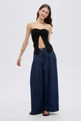 Top de viscosa negro, sin mangas, con escote strapless y frunce central en el escote que genera una abertura frontal.