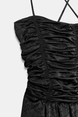 Mono largo de pierna ancha con escote recto y cuerpo superior con frunces. Presenta tirantes finos ajustables que se cruzan en la espalda y cierre lateral oculto.