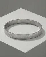 Esclava rígida de acero inoxidable con diseño grabado de guarda griega en toda su superficie.